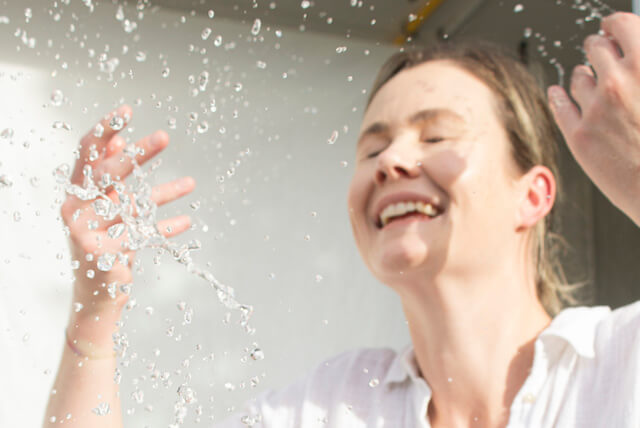 The Best Natural Routines For Acne - Girl smiling into a mirror while admiring her acne-free skin