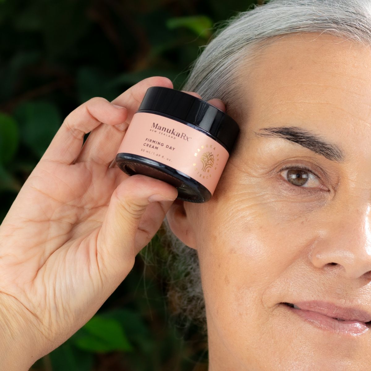 A woman holding a pot of ManukaRx Firming Day Cream