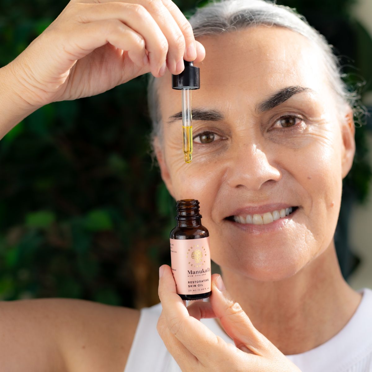 Woman holding bottle of ManukaRx Restorative Skin Oil