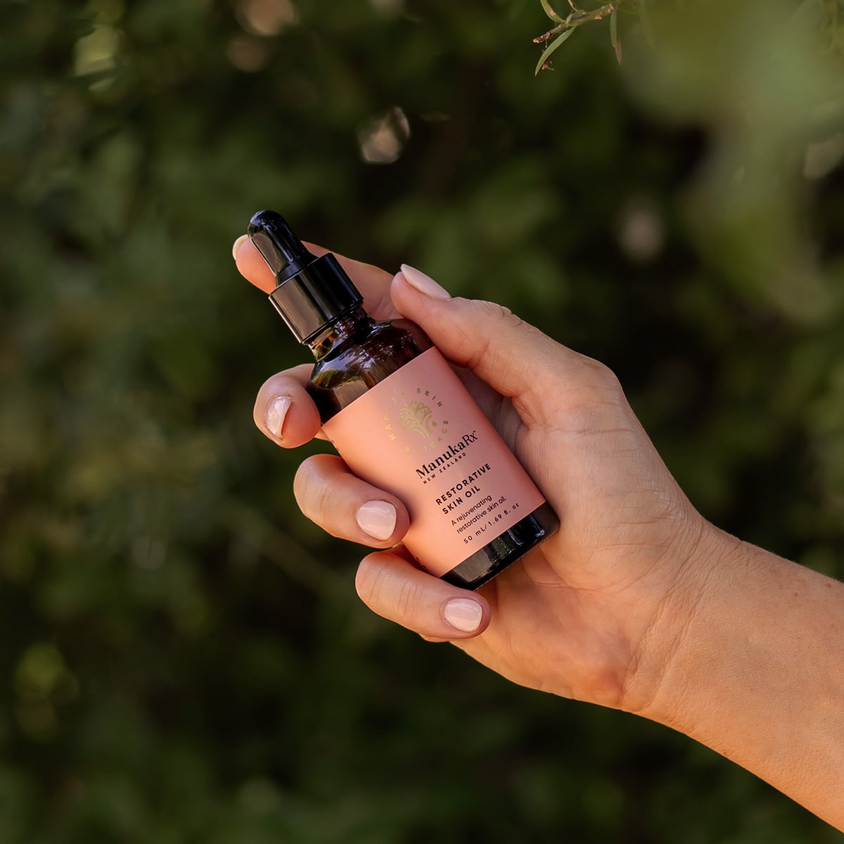Woman's hand holding bottle of ManukaRx Restorative Skin Oil