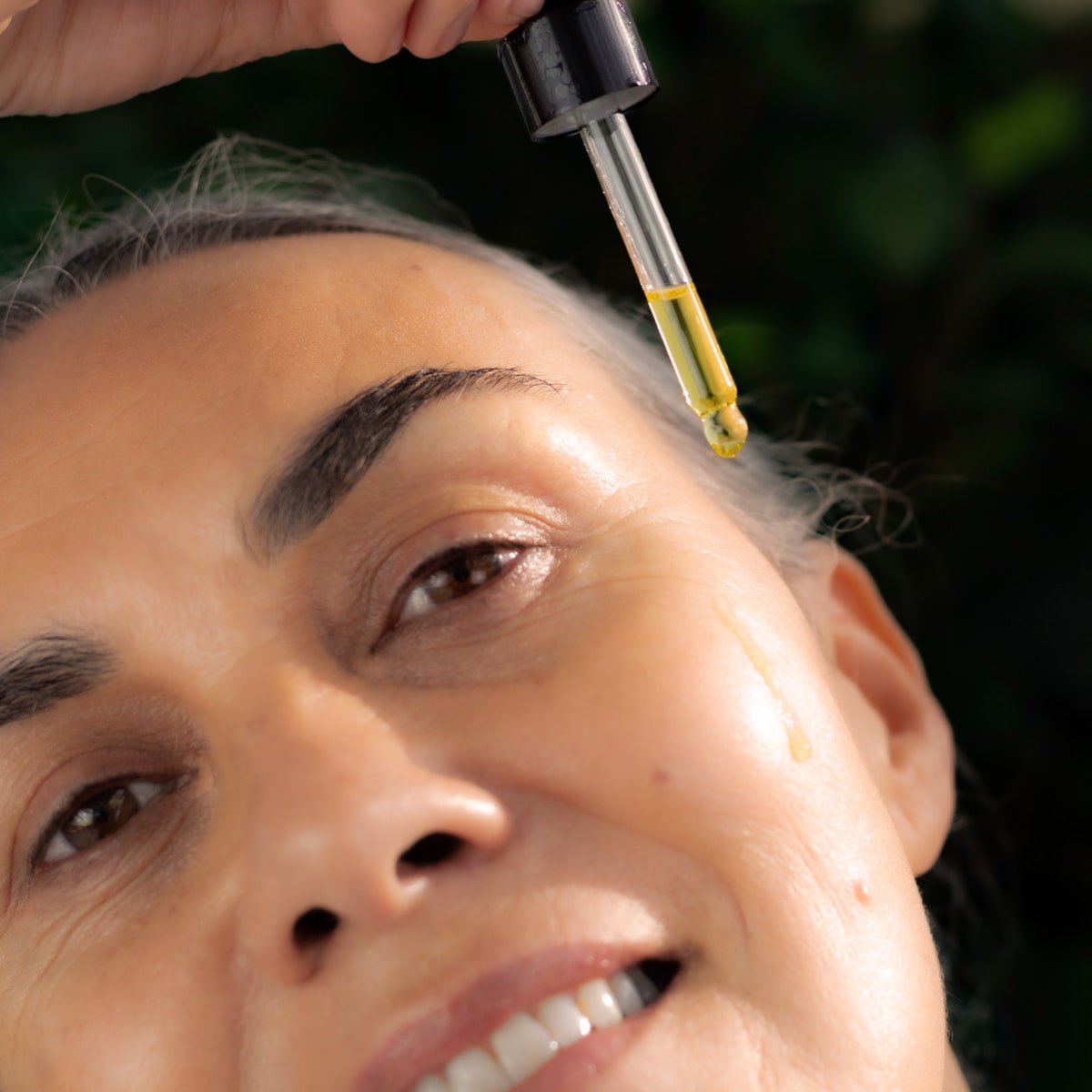 Woman dropping Restorative Skin Oil onto her face