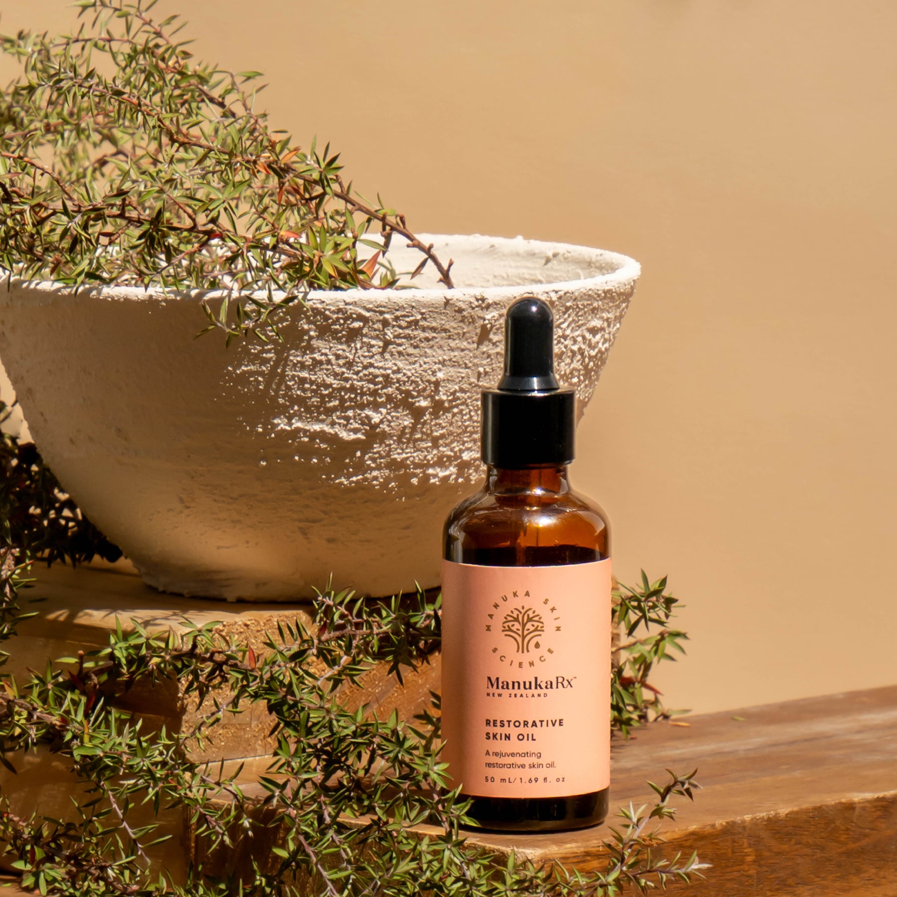 ManukaRx Restorative Skin Oil beside Mānuka plant cuttings